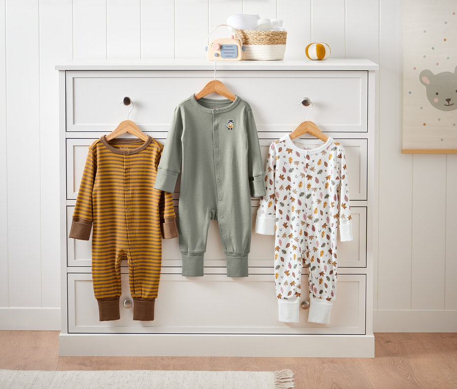 Drei Pyjamas hängen an einer Kommode.