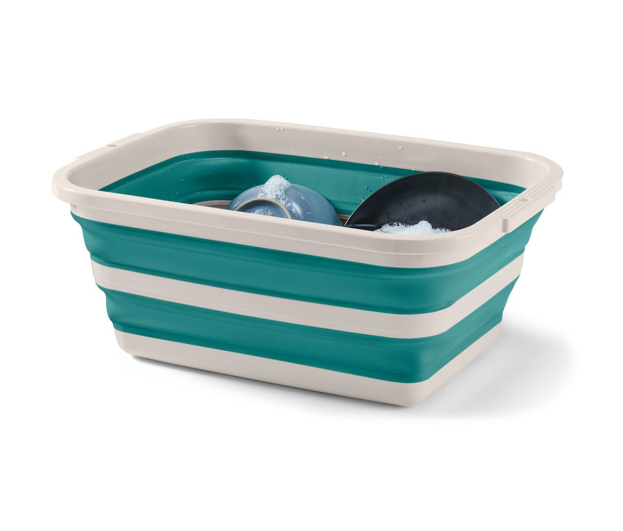 Schmutziges Geschirr in faltbarem Wäsche- und Spülkorb in Grün und Weiß.