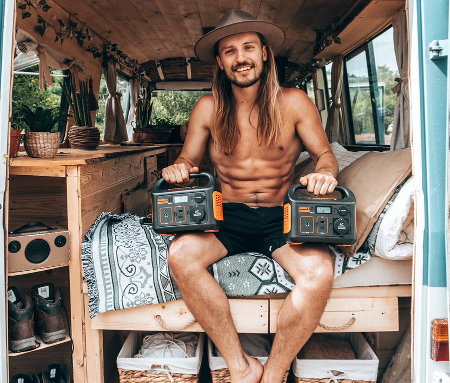 Mann sitzt im Heck eines Lieferwagens und hält zwei Jackery Explorer 240 Stromversorgungen.