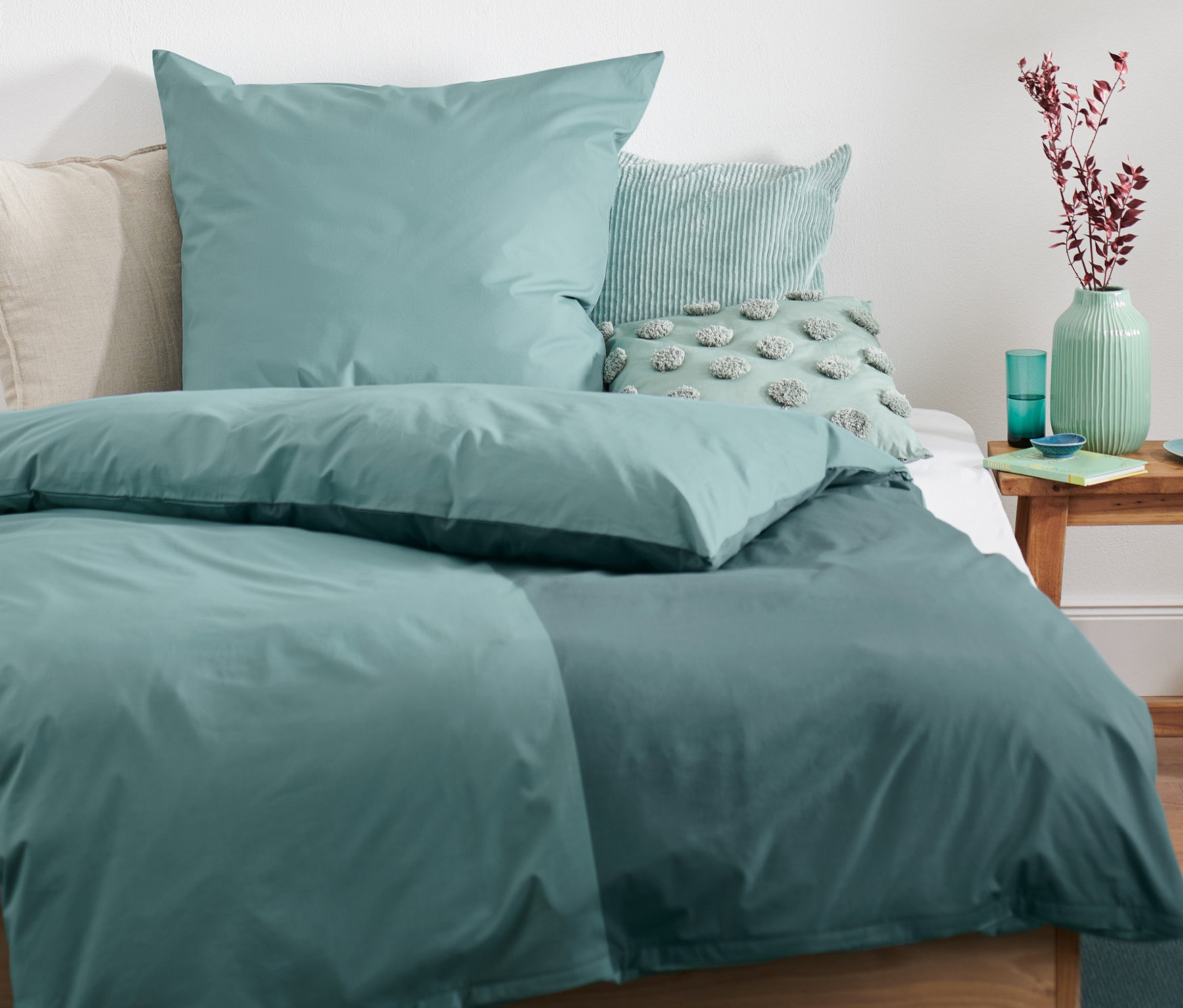 Grüne Premium Baumwoll-Bettwäsche verschiedener Größen auf einem Bett.