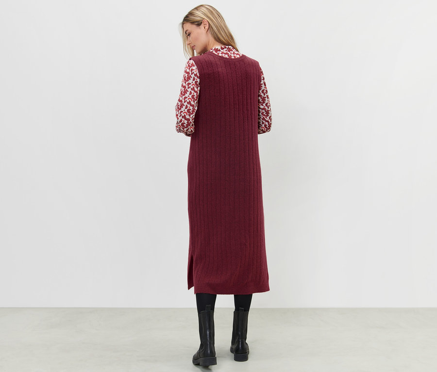 Frau steht mit dem Rücken und trägt ein geripptes Strickkleid in Rot.