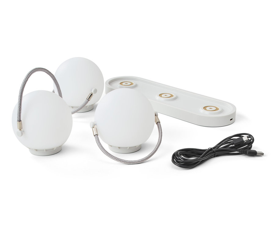 Drei Akku-Tischleuchten, eine Ladestation und ein Kabel auf weißem Hintergrund.