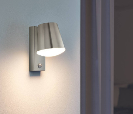 Eine Eglo Outdoor-Wandleuchte »Caldiero« leuchtet an einer Wand neben einem Fenster.