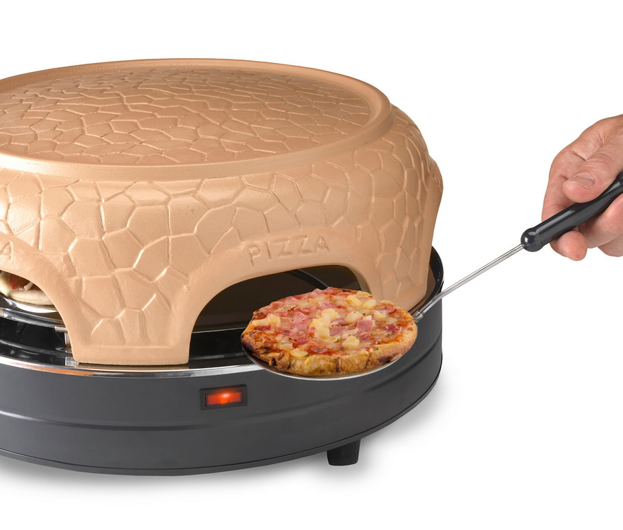 Eine Hand hält eine Pizza auf einem Pizzaschieber vor einem braunen Pizzaofen.