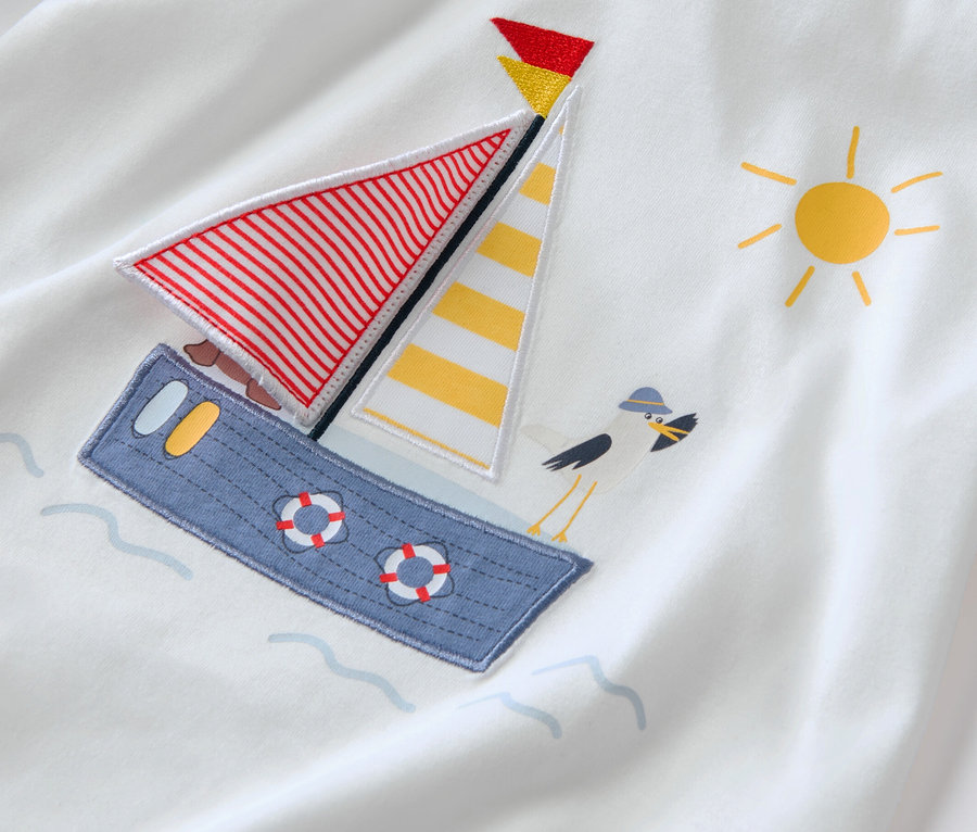 Detail eines weißen T-Shirts mit einer Applikation eines maritimen Bootes und einer Möwe.