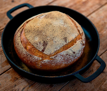 Ein Brotlaib in einer COMBEKK Gusseisen-Servierpfanne »Sous-Chef« auf einem Holztisch.