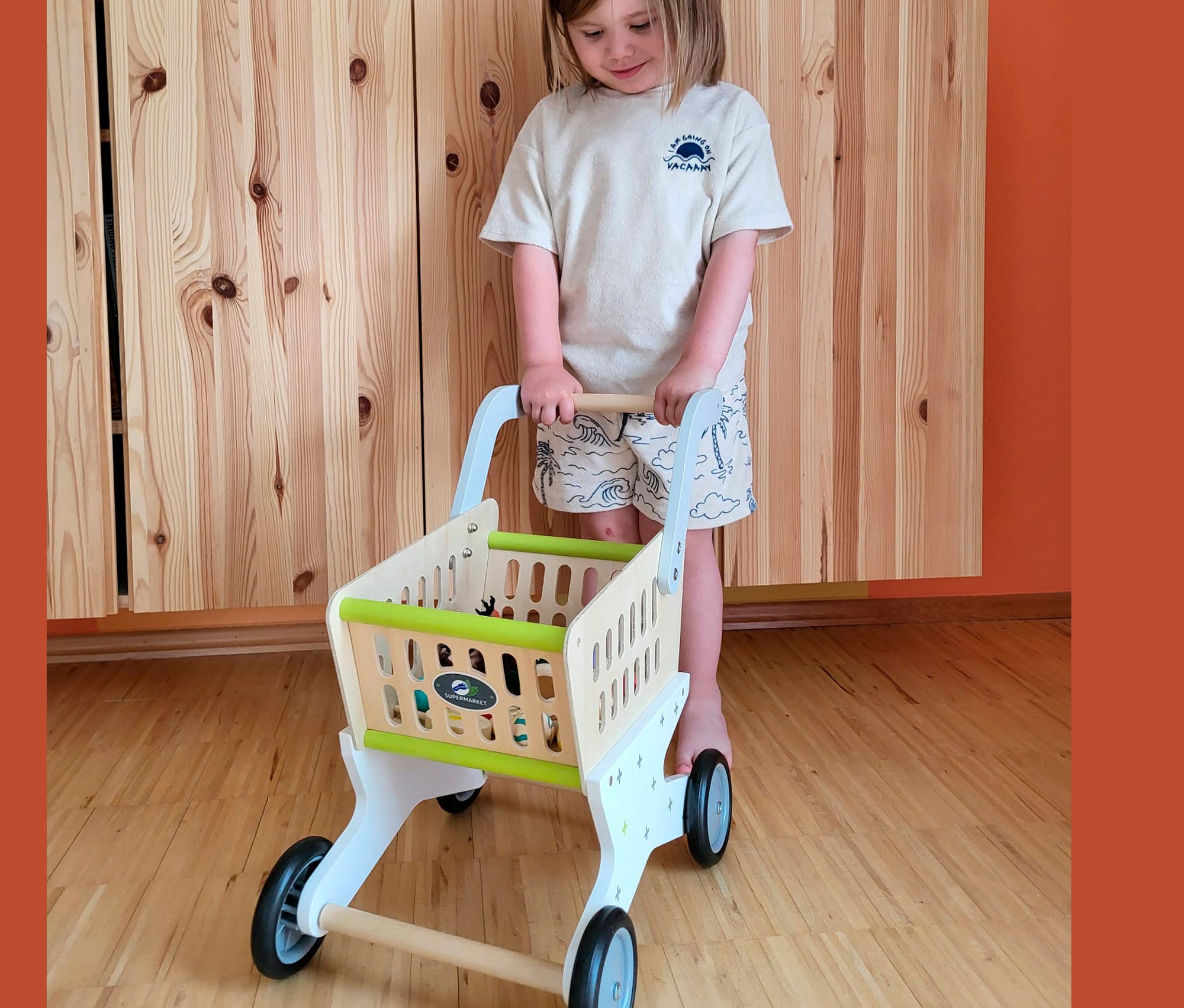 Mädchen schiebt einen »Trend« Einkaufswagen von small foot aus Holz in einem Kinderzimmer.