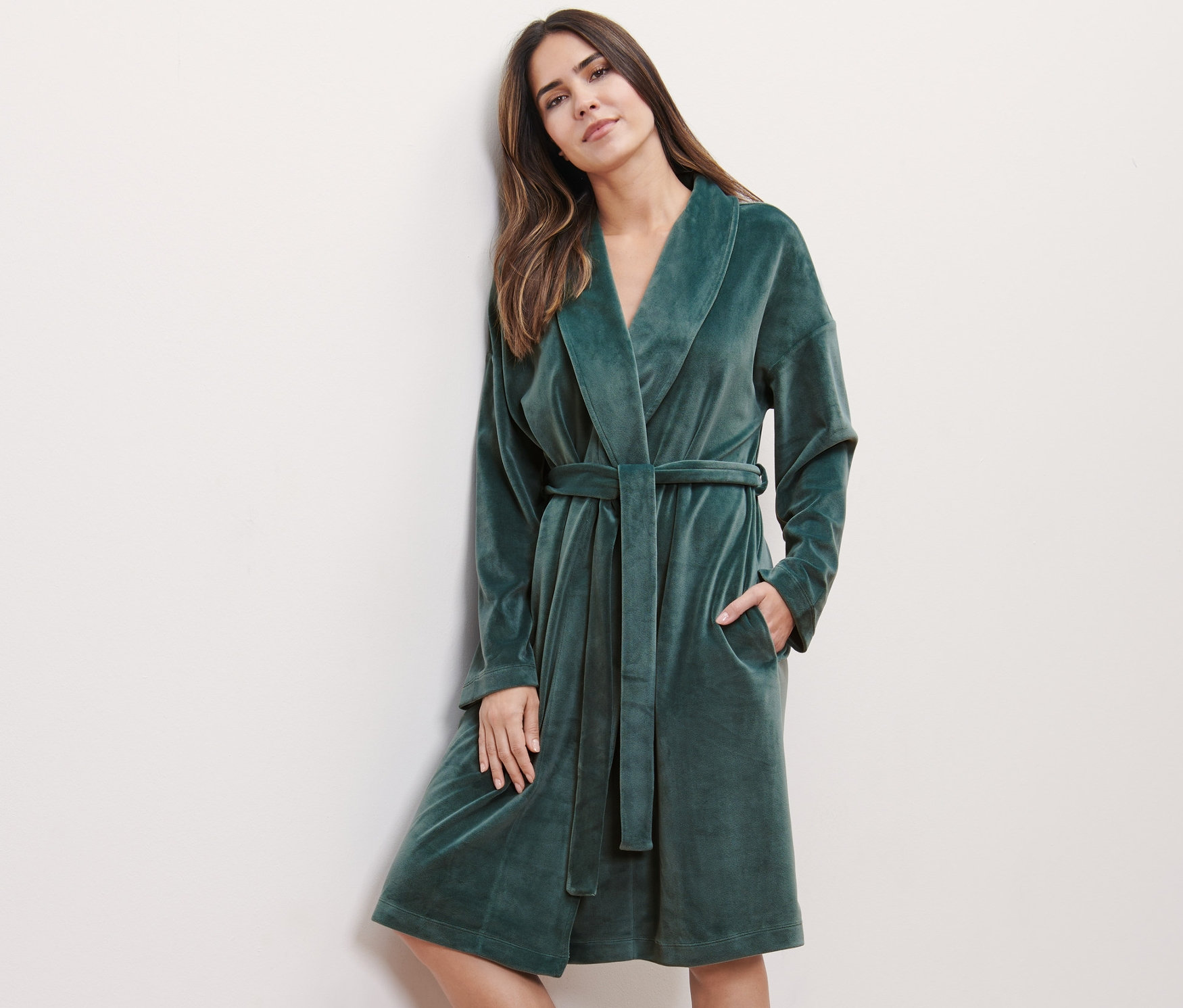 Frau lehnt an Wand und trägt Nicki-Morgenmantel.