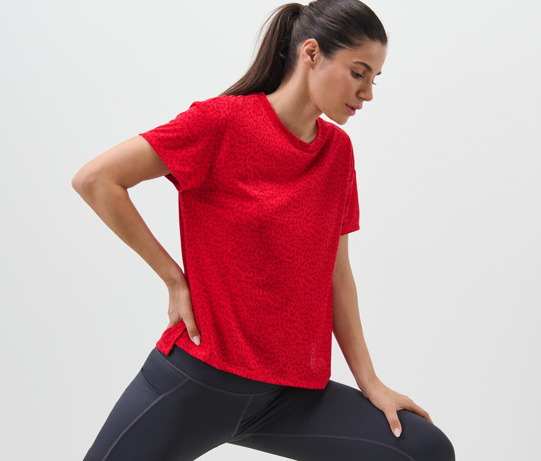 Frau dehnt sich in einem roten Sportshirt.