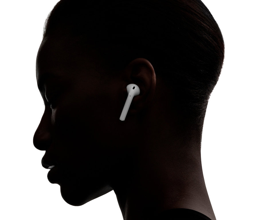 Profil einer dunkelhaarigen Person mit einem weißen Ohrhörer im Ohr. Apple AirPods 2. Generation.
