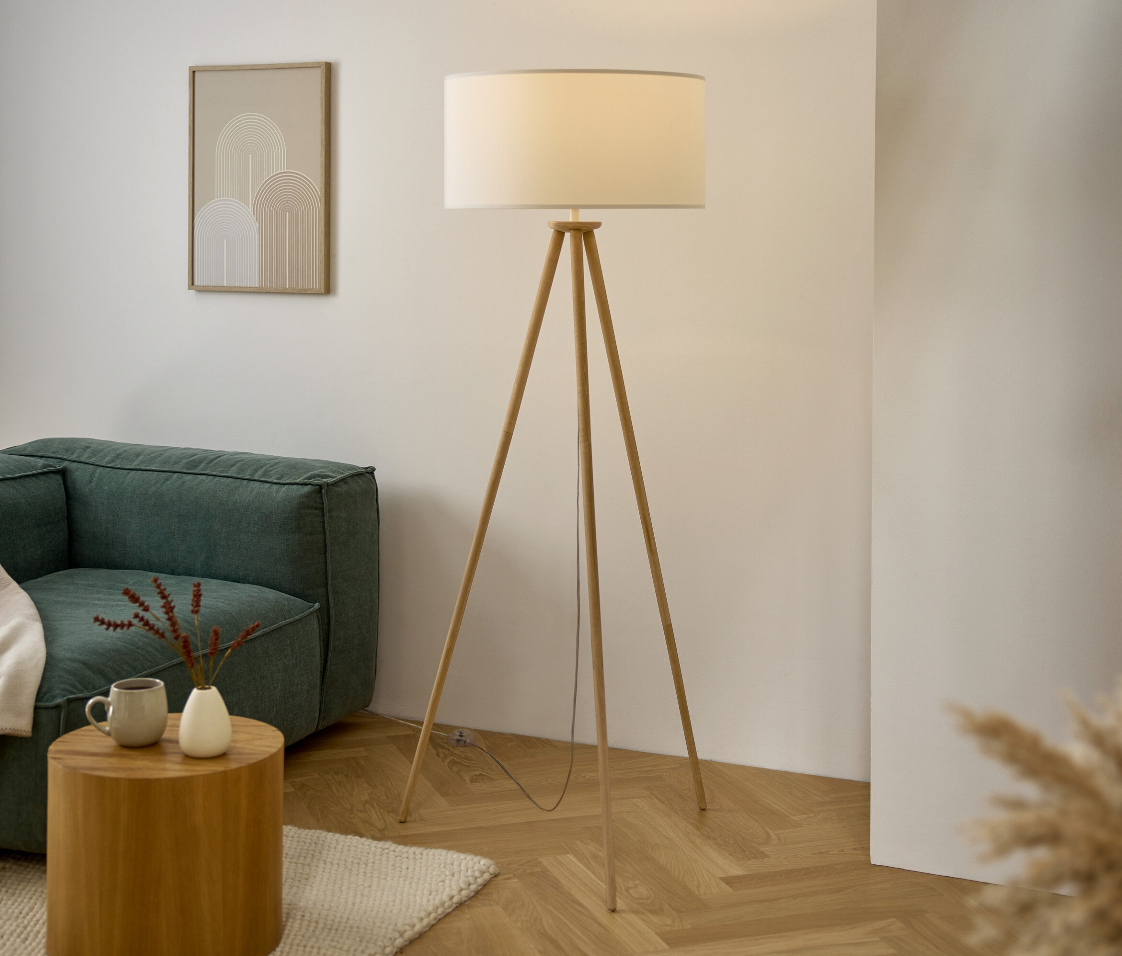 Wohnzimmer mit Sofa, Holztisch, Stativlampe und Kunstwerk an der Wand.