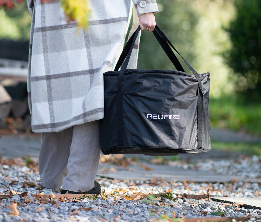 Person hält eine schwarze RedFire Feuerschale »Volcano Extra Large«-Tasche.