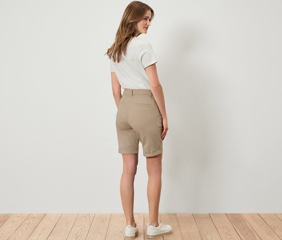 Frau steht mit dem Rücken zur Kamera und trägt eine beige Chino-Shorts.