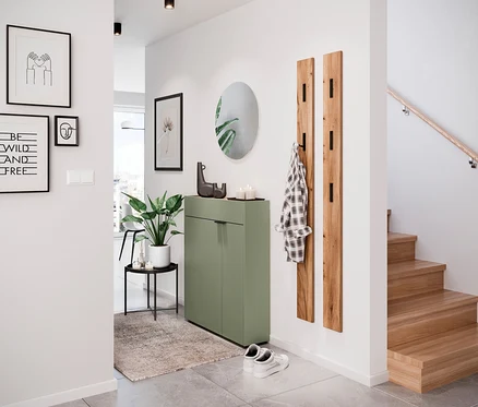 Eingangsbereich mit Rahmen an den Wänden, grünem Schrank, Spiegel, Kleiderständer und Treppe.