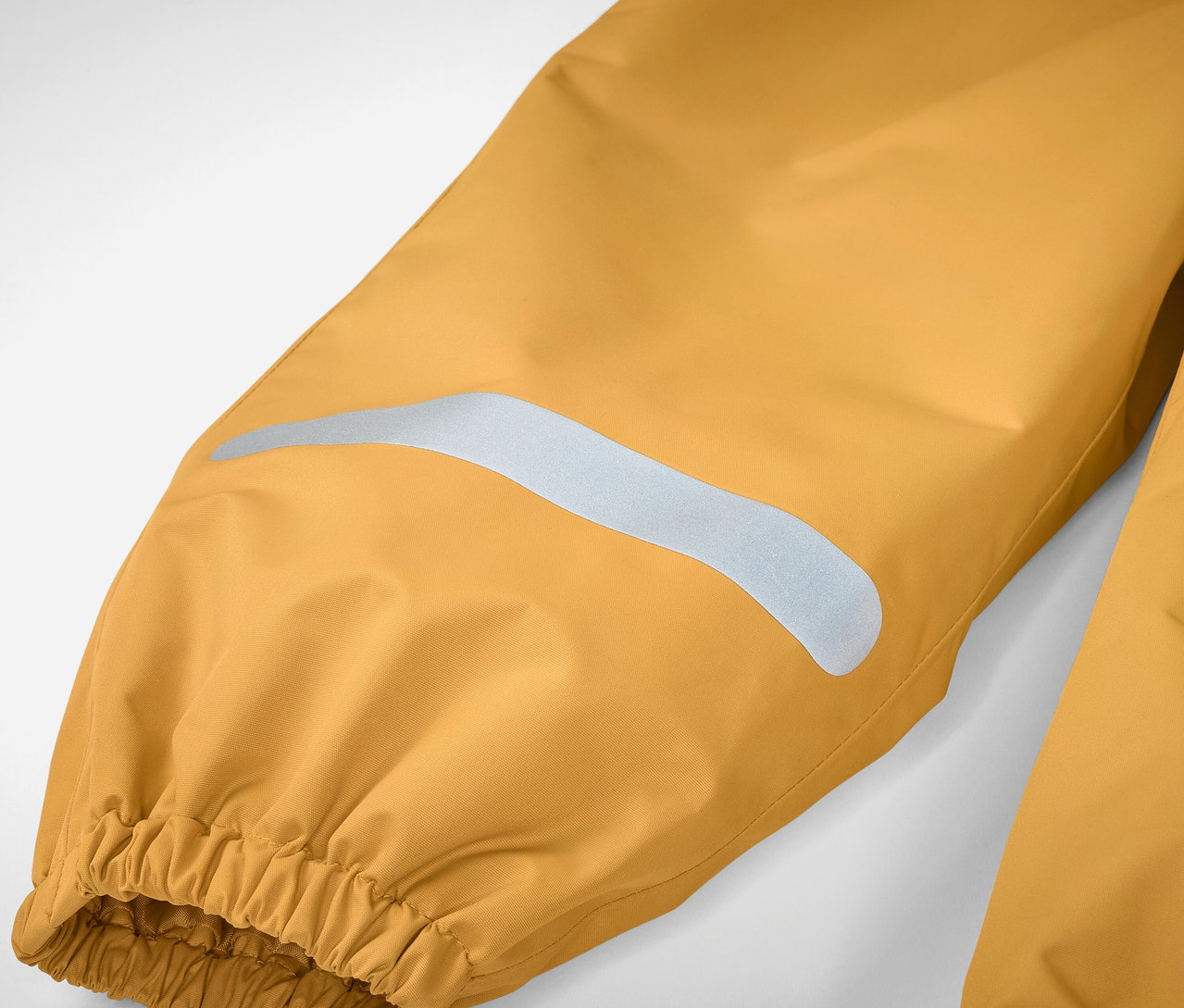 Detail einer gelben Kinder-Regenhose mit Reflektorstreifen und Gummizug.