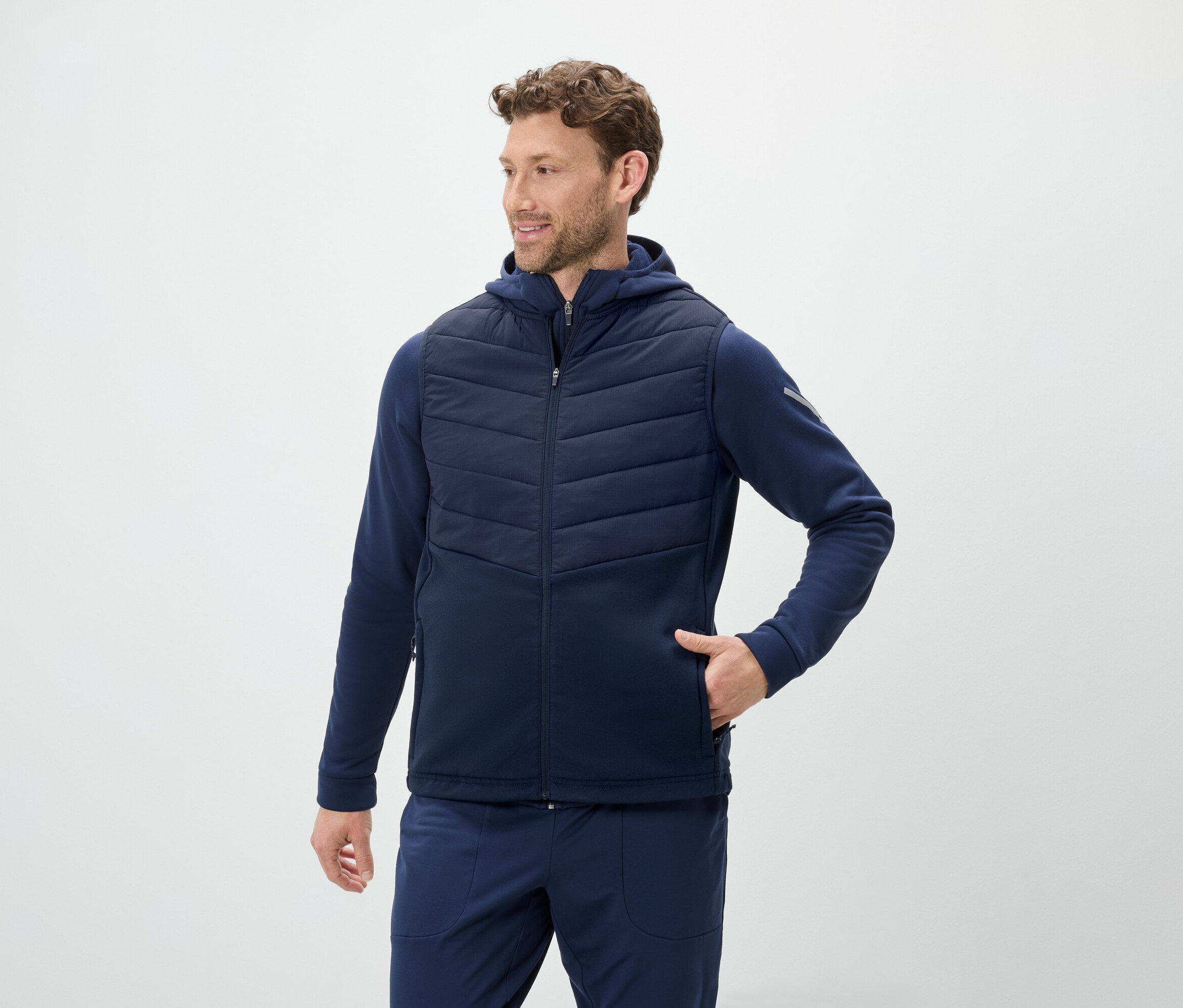 Mann trägt eine blaue Weste mit Kapuze und eine blaue Jogginghose.