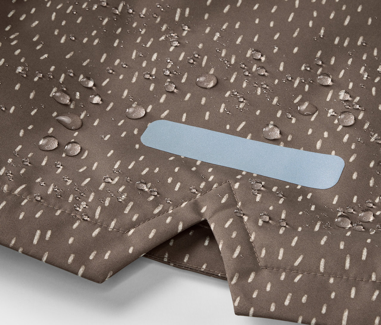 Detailaufnahme einer Kinder-Thermo-Regenjacke mit Wassertropfen und Reflektor.