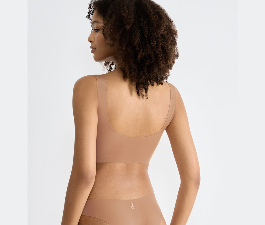 Rückansicht einer Frau mit braunem lockigem Haar, die ein Sloggi ZERO Feel 2.0 Top in nostalgischem Braun und Höschen trägt.