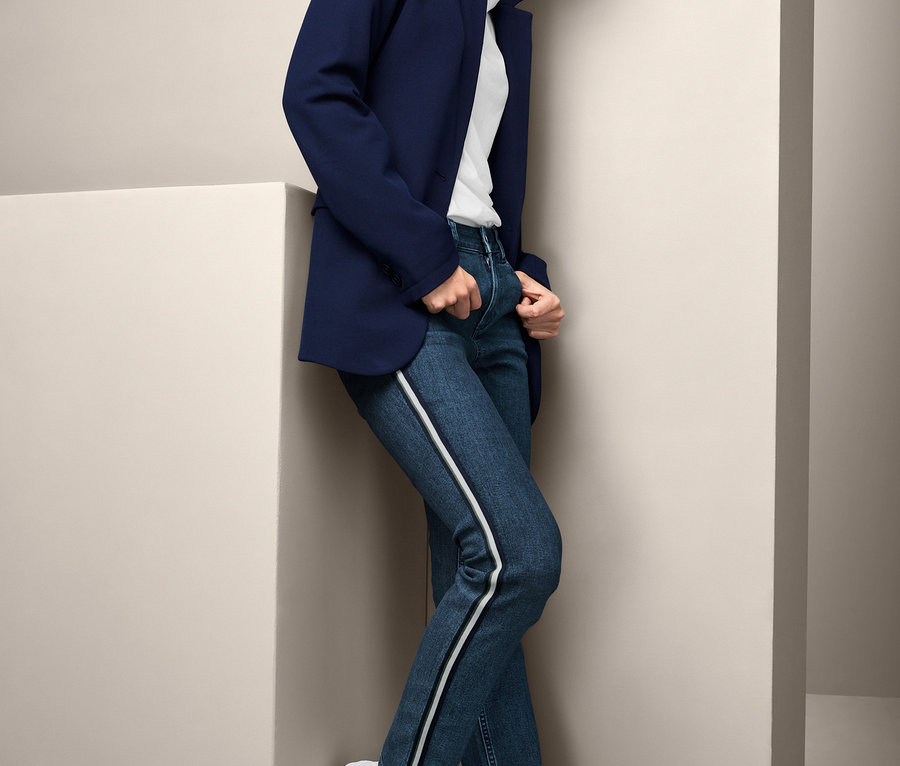 Frau posiert in marineblauem Blazer und Jeans mit Galonstreifen.