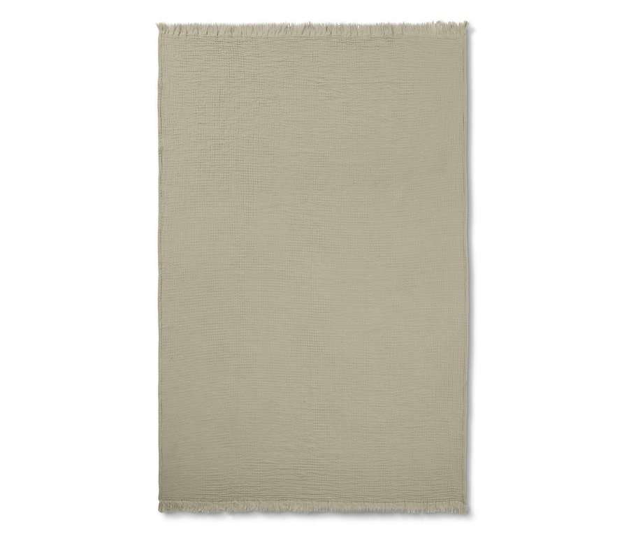Eine beige Musselin-Plaid mit Fransen liegt auf einem weißen Hintergrund.