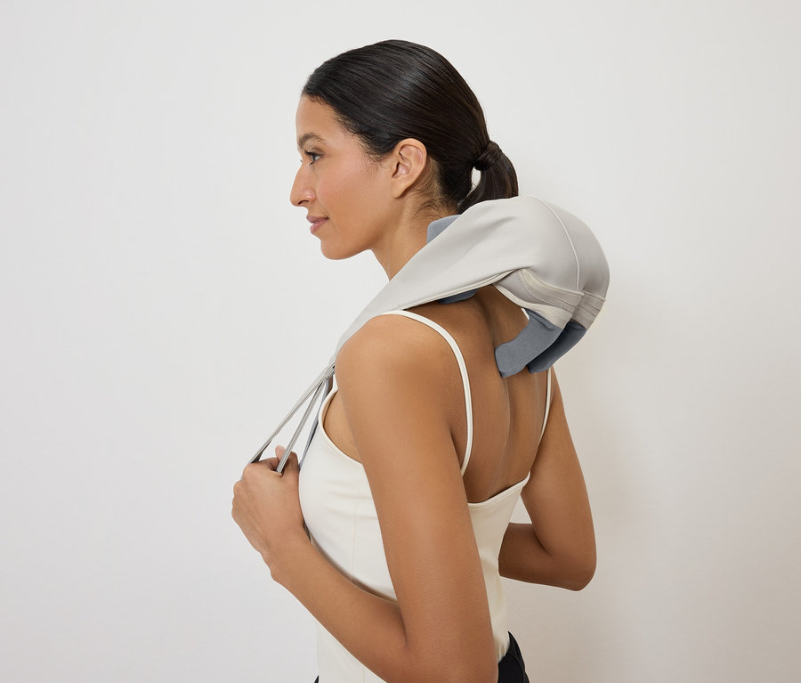 Frau mit Nackenmassagegerät, seitliche Ansicht.