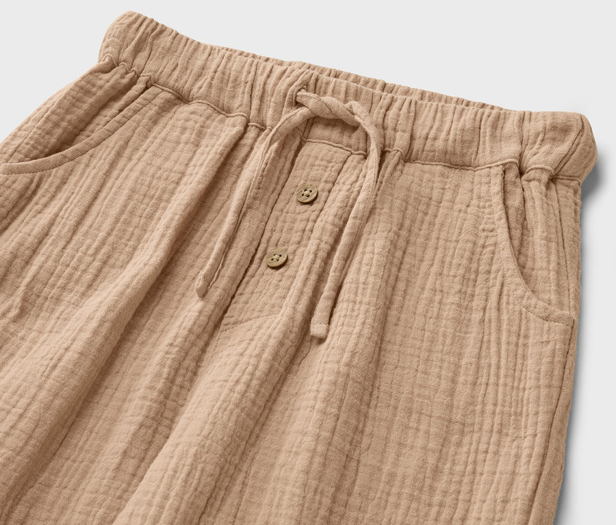 Detailaufnahme einer Kinder-Musselin-Hose mit Kordelzug und Knöpfen.