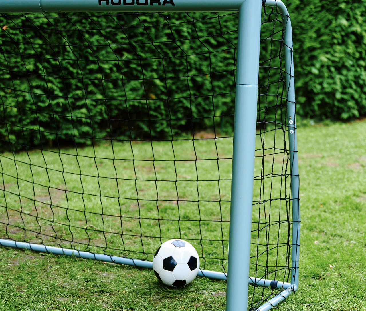 Auf Rasen steht ein graues HUDORA Fußballtor "Expert 300" mit schwarzem Netz und einem weißen Fußball.