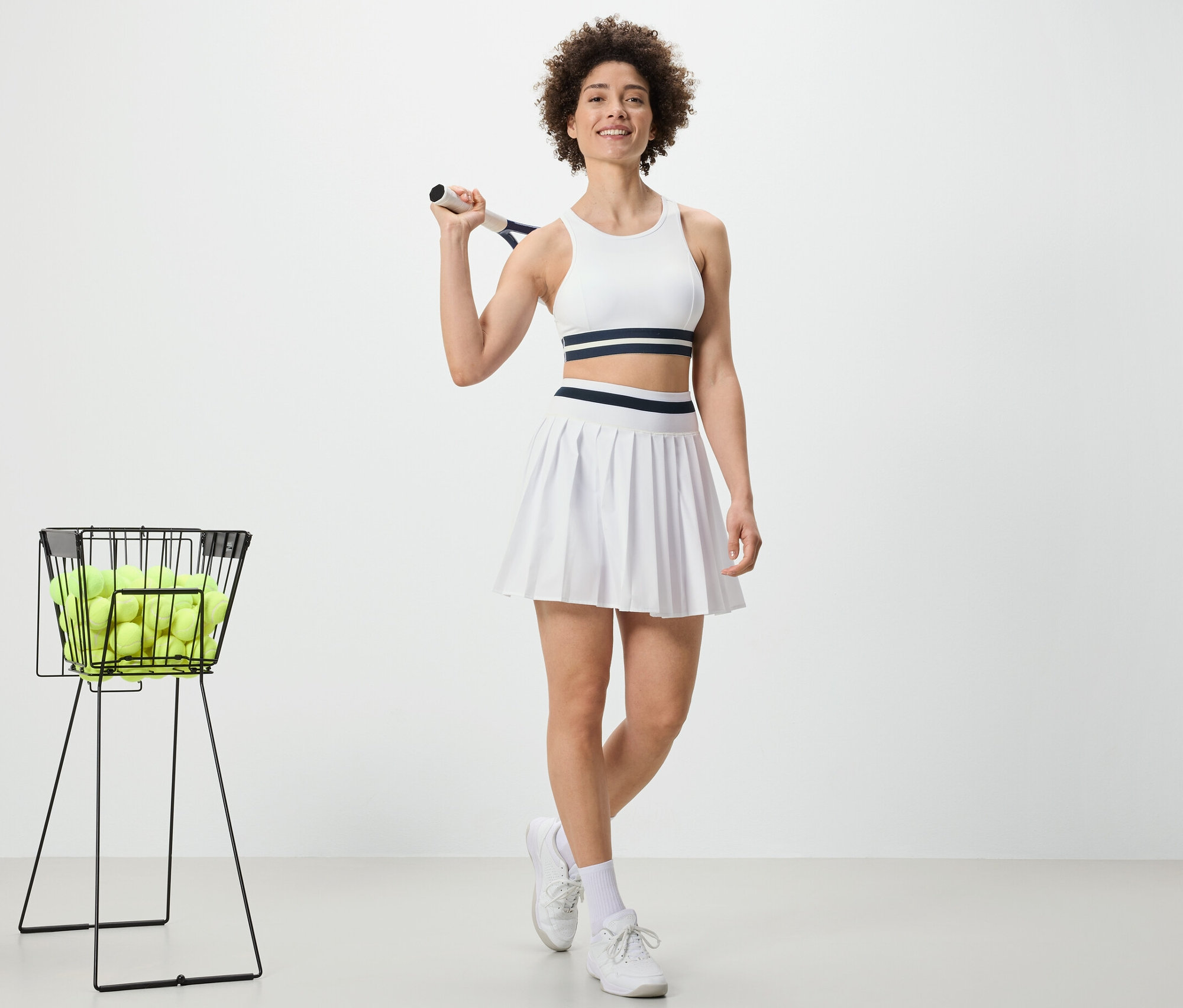 Frau hält Tennisschläger und trägt Sportrock.