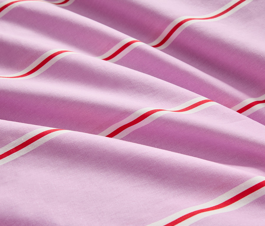 Nahaufnahme von gefaltetem, gestreiftem, rosa Stoff mit roten und weißen Streifen.