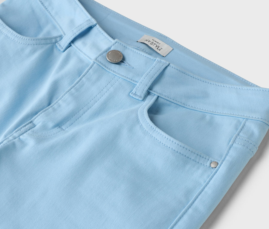 Detailaufnahme einer hellblauen Hose mit Knopf und Tasche.