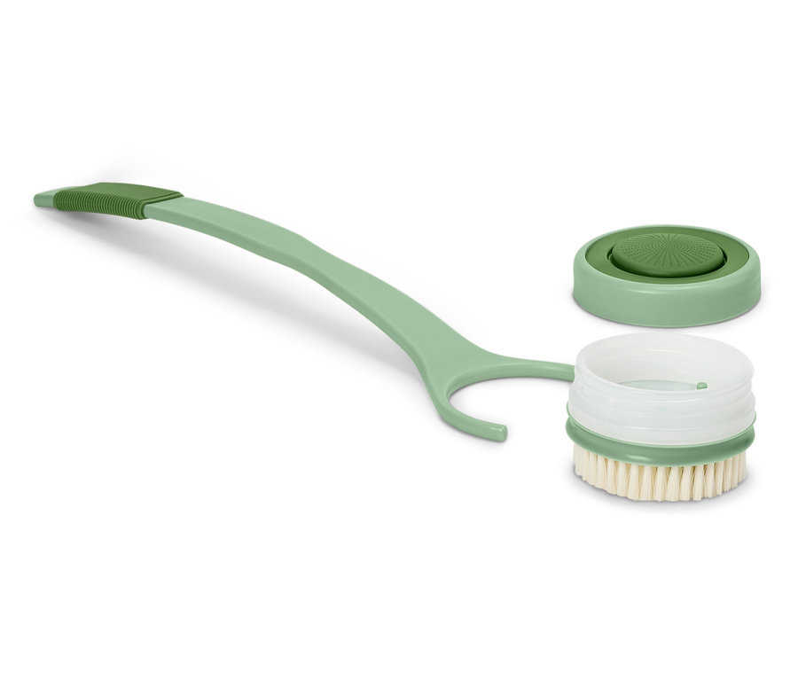 Eine grüne Bürste mit langem Griff liegt neben einem abgenommenen Deckel.