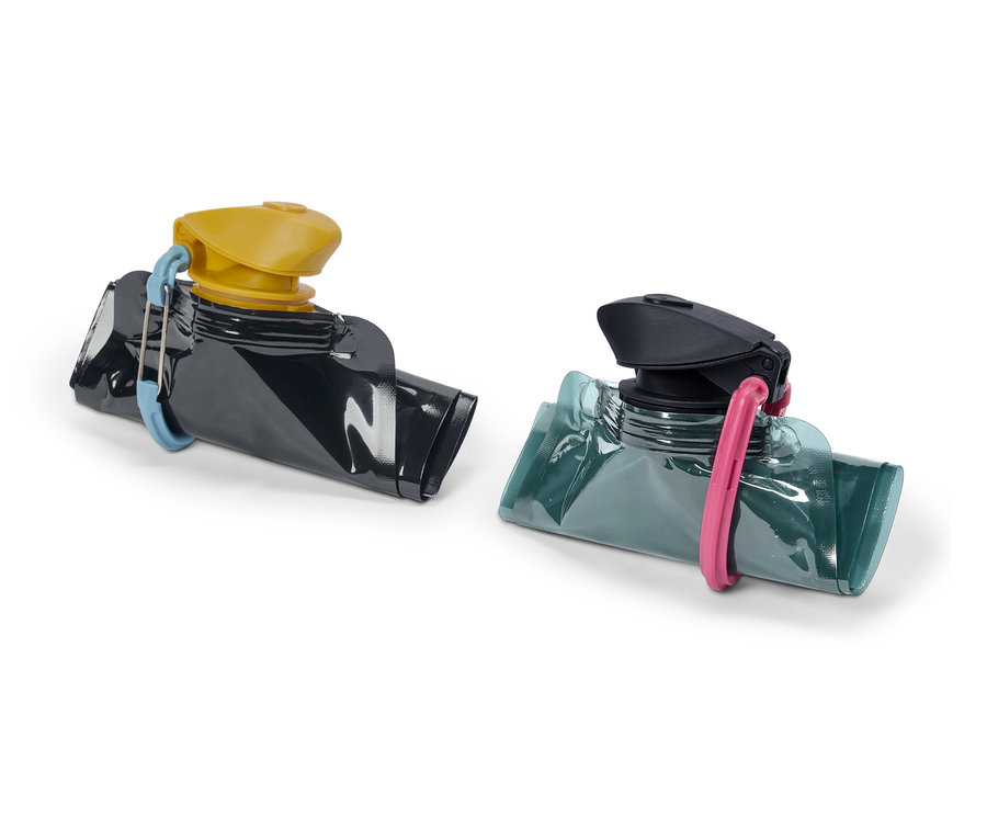 Zwei wiederverwendbare Quetschbeutel, einer schwarz mit gelbem Deckel und blauem Clip, der andere blaugrün mit schwarzem Deckel und pinkfarbenem Clip.
