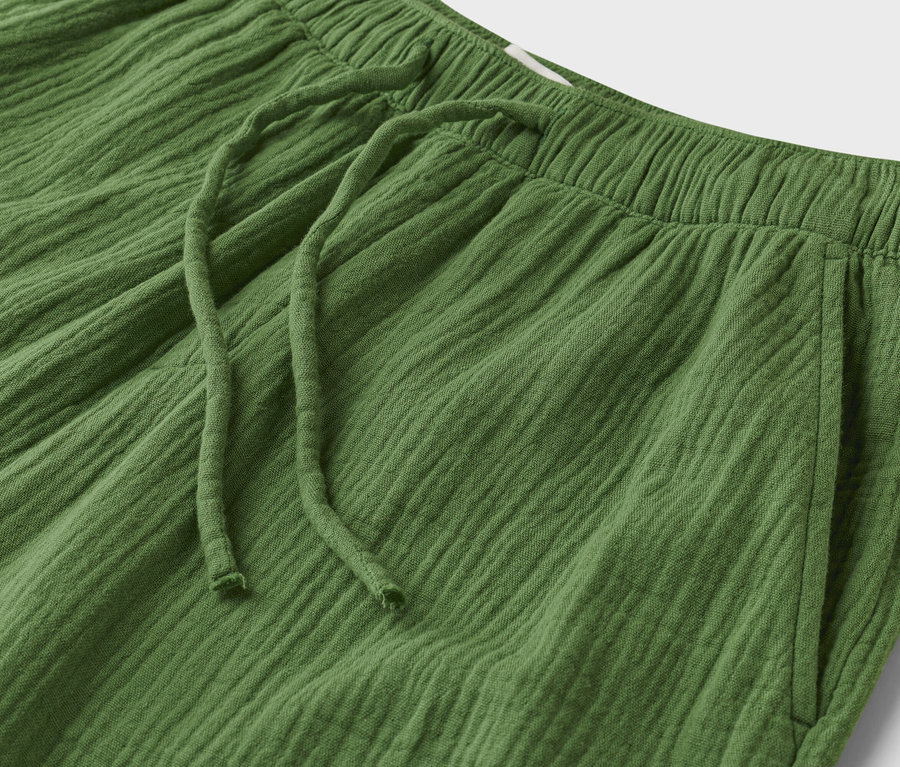 Nahaufnahme einer grünen, texturierten Hose mit Kordelzug und elastischem Bund.