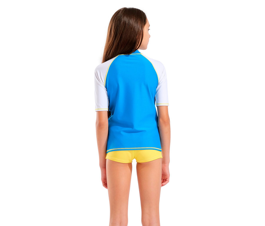 Rückansicht eines Mädchens mit braunen Haaren, das ein blaues und weißes Rashguard-Shirt und gelbe Shorts trägt.