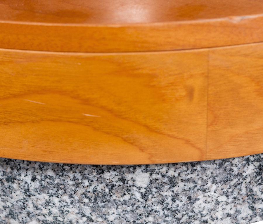 Nahaufnahme einer runden Holzschale auf einer grauen, gesprenkelten Granitbasis.