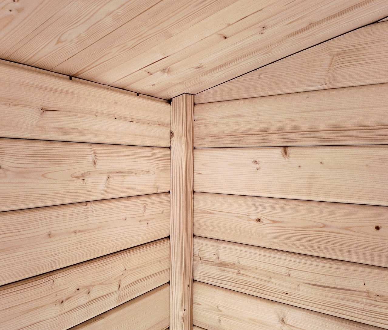 Helle Holzbretter bilden eine Ecke, verbunden durch einen vertikalen Holzpfosten.