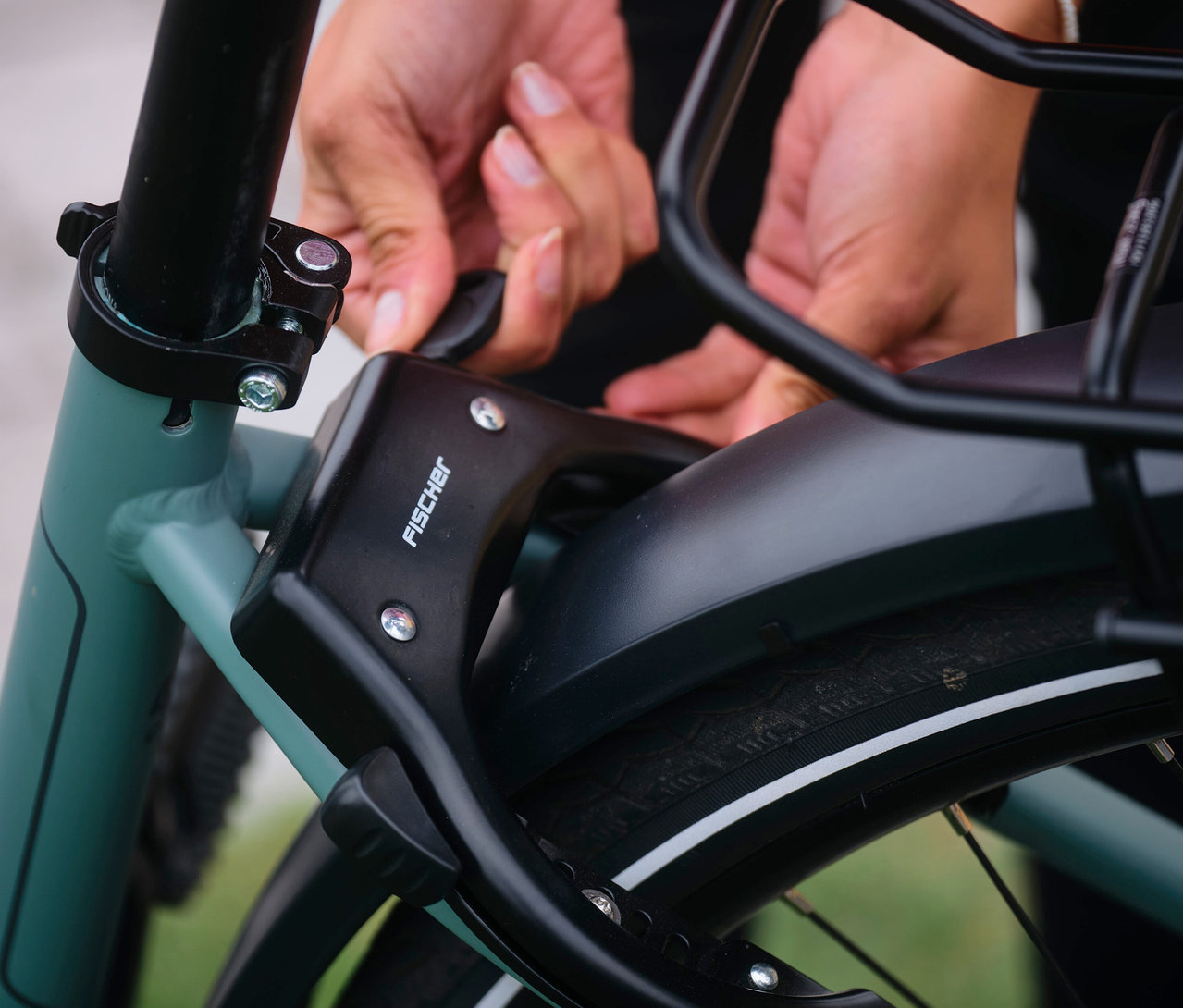 Nahaufnahme einer Person, die ein schwarzes Bügelschloss an einem Fischer Trekking E-Bike VIATOR 2.1 ACTIVE befestigt.
