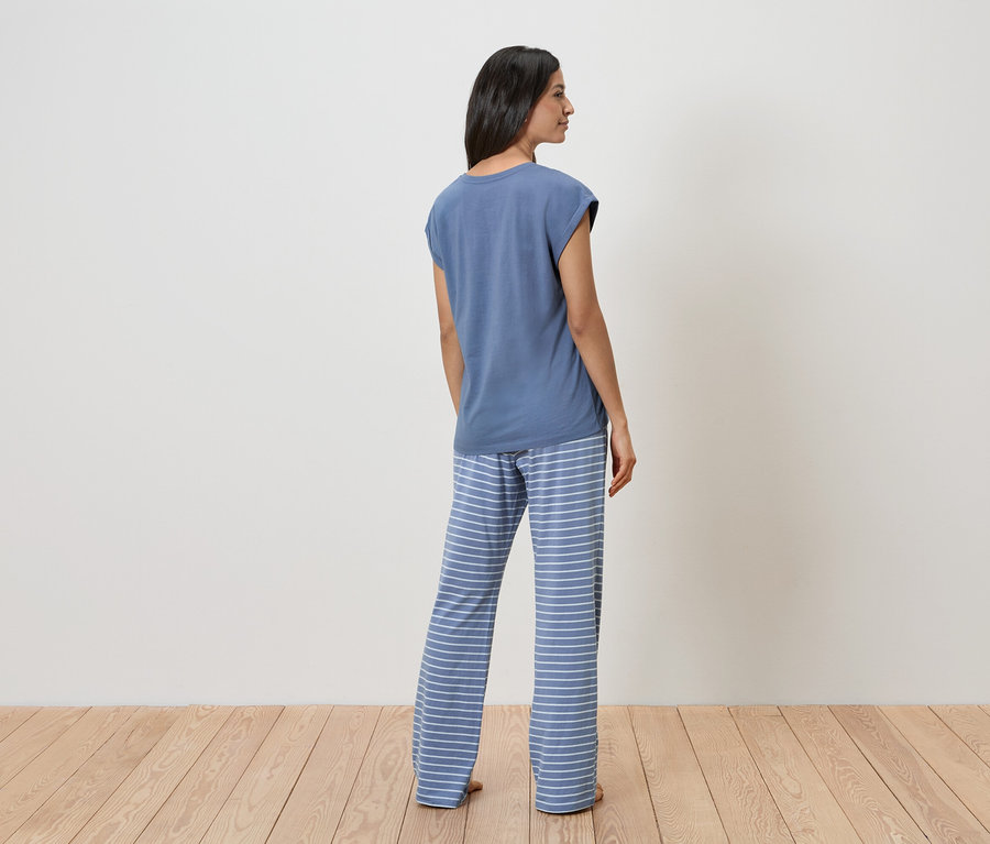 Frau von hinten in blauem T-Shirt und gestreifter Hose.