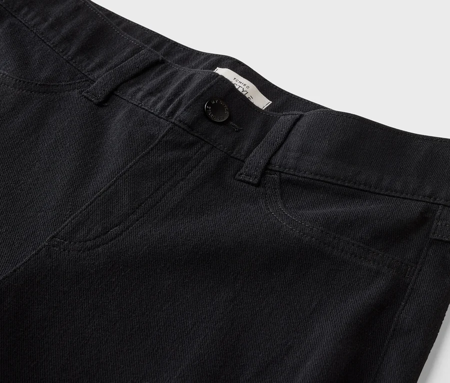 Nahaufnahme der Vorderseite einer schwarzen Jeans mit Knopf und Taschen.