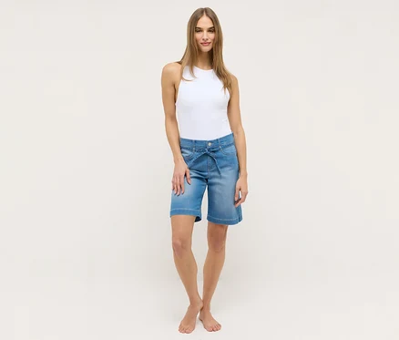 Frau in weißem Top und Angels Denim »Lia City« Shorts, hellblau, mit Bindegürtel.