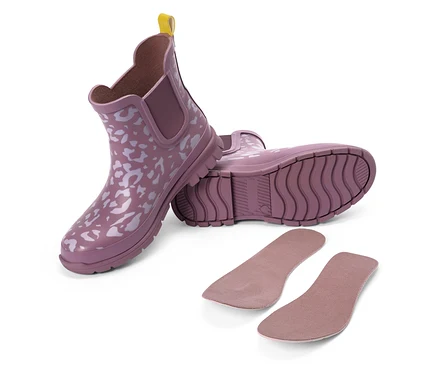 Zwei lila Gummistiefel mit weißem Muster und gelber Lasche, daneben zwei Einlegesohlen.