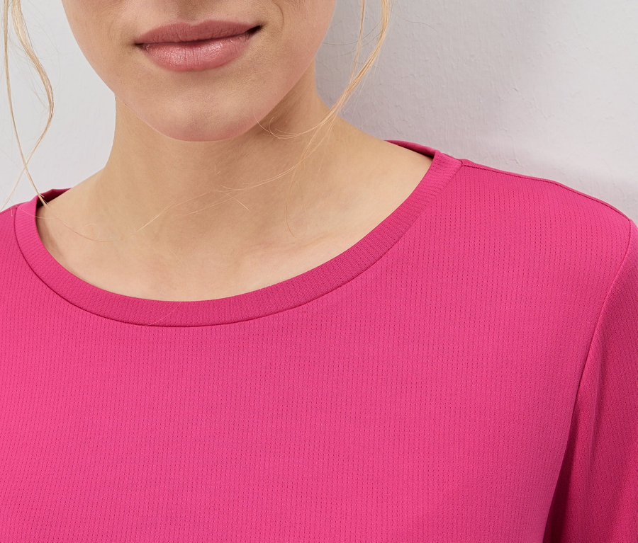 Nahaufnahme einer Frau, die ein pinkfarbenes Oberteil trägt.