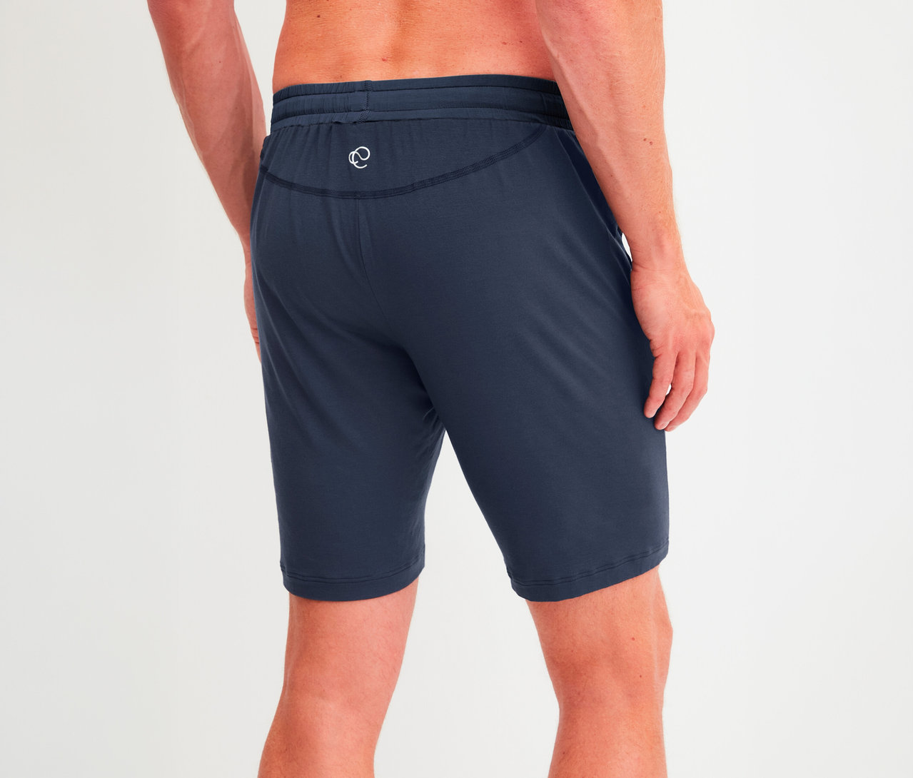 Mann von hinten, trägt dunkelblaue Shorts mit Kordelzug und weißem Logo am Gesäß.