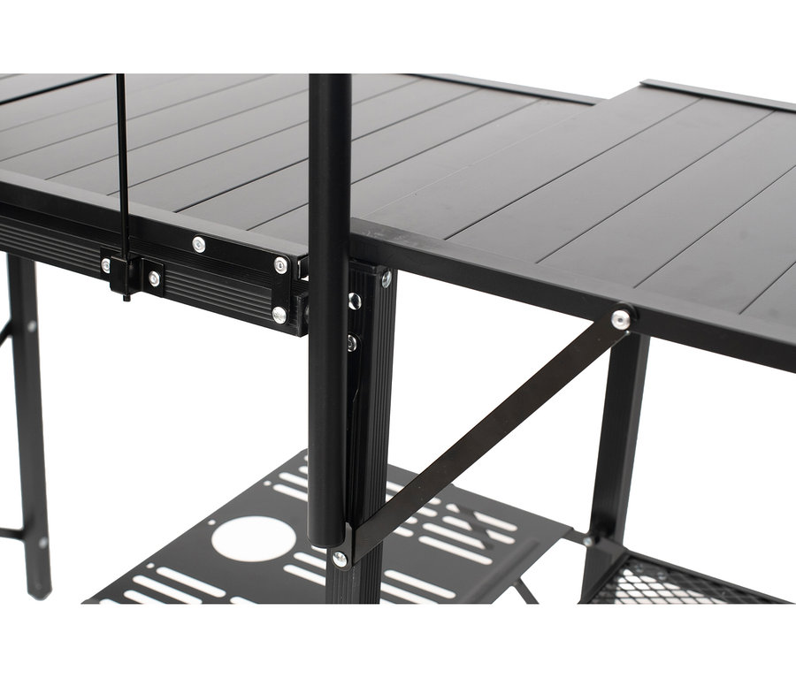 Nahaufnahme der schwarzen faltbaren Campingküche „Elmwood“ mit einer Lamellenplatte, einem perforierten Mittelboden und einem Gitterboden, mit sichtbaren Metallstützen und Scharnieren.