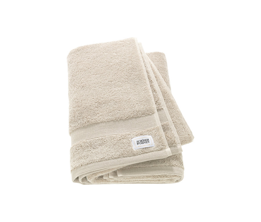 Zwei sandfarbene, gefaltete Badetücher der SCHÖNER WOHNEN-Kollektion „Cuddly“ liegen übereinander, mit sichtbarem Etikett.
