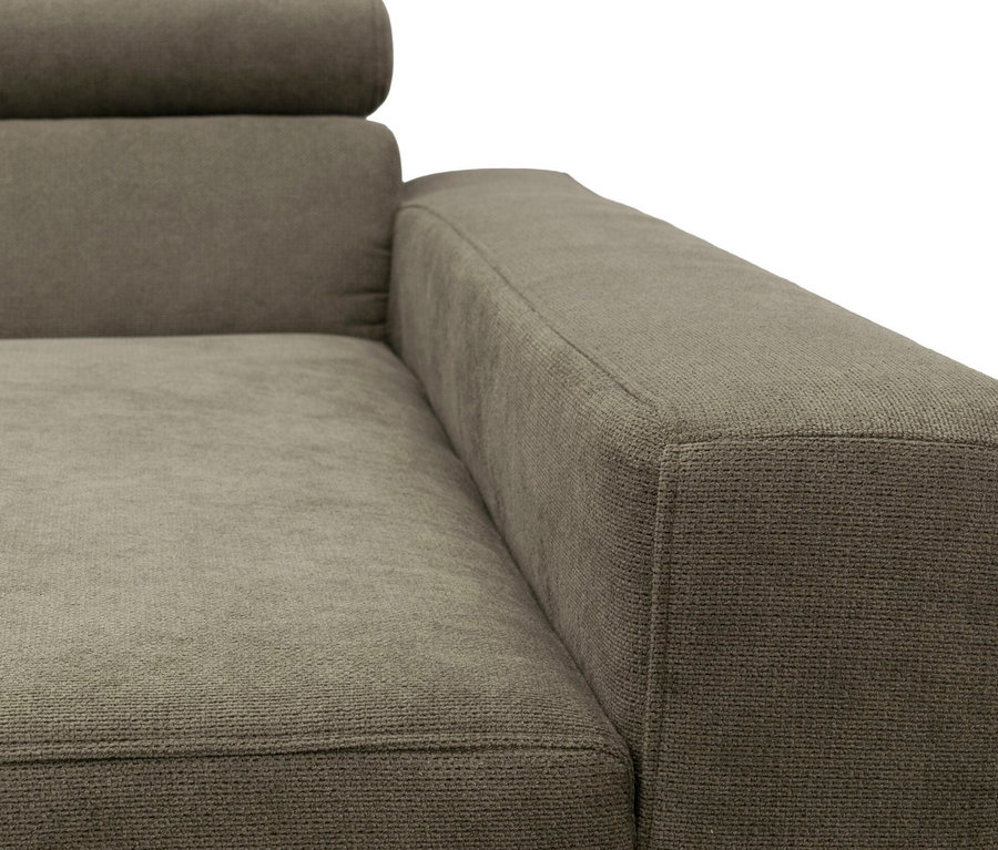Nahaufnahme eines grau-grünen Sofas mit strukturierter Oberfläche, das die Armlehne, den Sitz und einen Teil der Rückenlehne mit Kopfstütze zeigt.