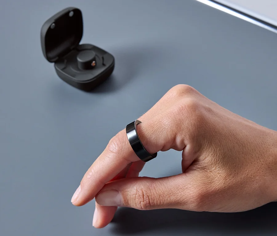 Eine Hand trägt einen schwarzen Ring. Neben dem Ring befindet sich eine offene Hülle.