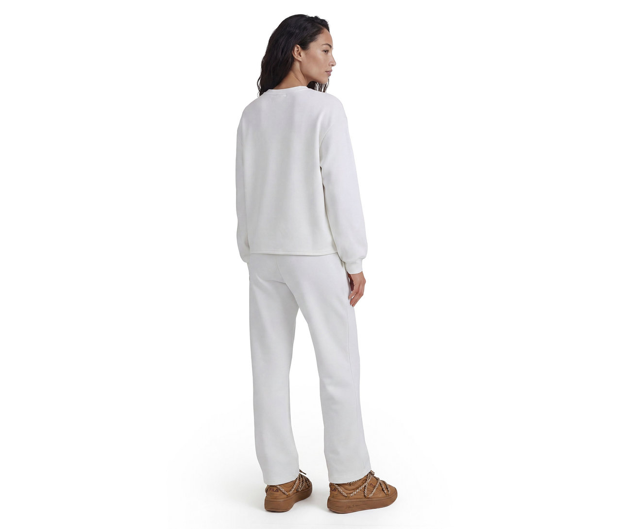 Frau von hinten in weißem Sweatshirt, weißer Jogginghose und braunen Schuhen mit Kettendetails.