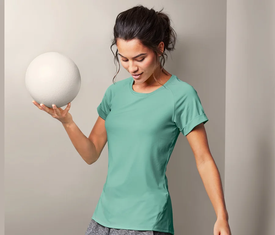 Frau hält einen weißen Ball und trägt ein Sportshirt.