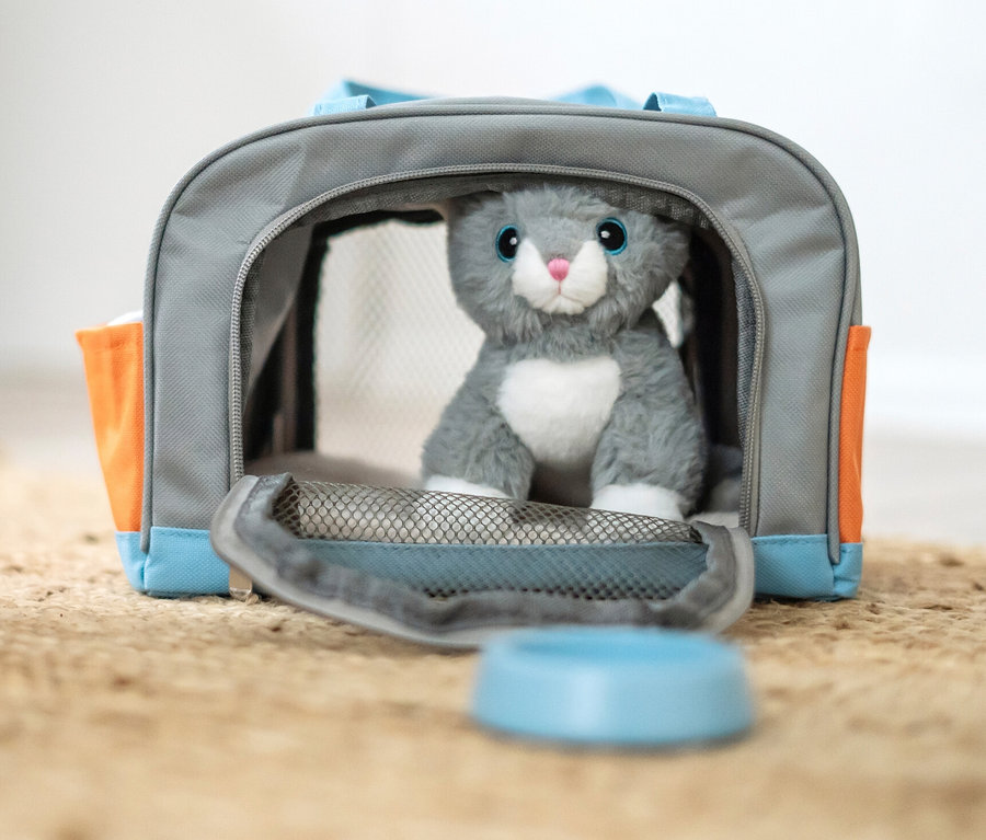 Kind spielt mit small foot Katze mit Tasche und Pflege-Set auf einem Jute-Teppich.
